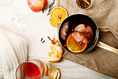 Scandinavian mulled wine in copper saucepan cooked with slices of orange, apple and thyme