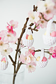 Easter eggs in crocheted baskets hung from flowering branch of fruit tree