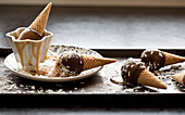 Chocolate covered ice cream cones on an antique baking sheet, with caramel and coconut