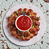 Pull-apart wreath bread with goat's cheese and rosemary served with marinara sauce
