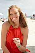 A blonde woman on a beach wearing an orange top