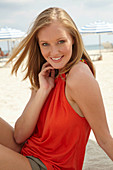 A blonde woman on a beach wearing an orange top