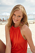 Blonde Frau in orangefarbenem Top am Strand