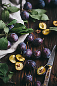 Damsons on a dark wooden surface with a linen cloth and a knife