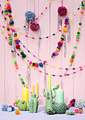 Colourful garlands of pompoms and ceramic cactus-shaped candlesticks