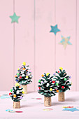 Mit Pompons dekorierte und bemalte Zapfen als Weihnachtsbäume
