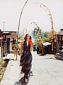 A young woman wearing a long summer dress with a feather print