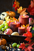 Harvest festival arrangement of candles, autumn fruits, pumpkins and autumn leaves