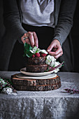 Woman's hand near chocolate cake on plate on wood stays