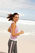 A young brunette woman jogging by the sea wearing sports clothes