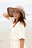 A brunette woman wearing a short-sleeved cardigan and a hat