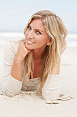 A blond woman on a beach wearing a light cardigan