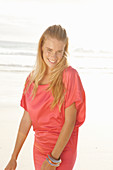 Blonde Frau in rotem Kleid am Strand