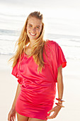 Blonde Frau in rotem Kleid am Strand