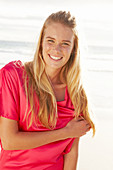 Blonde Frau in rotem Kleid am Strand