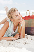 Blonde Frau in hellem T-Shirt am Strand liegend