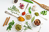 Fresh herbs and dried colorful spices in spoons and bowls arranged geometrically