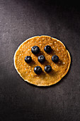 Ein Pancake mit Blaubeeren auf grauem Untergrund