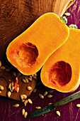 Halved butternut squash with seeds scattered on a chopping board