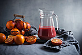 Blood orange juice in a glass jug with fresh fruit