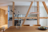 Dining area and simple fitted kitchen separated by wooden beams