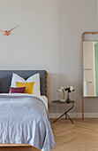 Double bed, bedside table and full-length mirror leaning against wall