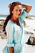 A brunette woman wearing a light-blue beach dress by the sea