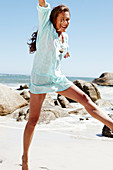 A brunette woman wearing a light-blue beach dress by the sea