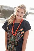 A young blonde woman with necklace wearing a beach dress