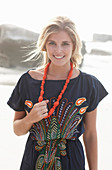 A young blonde woman with necklace wearing a beach dress