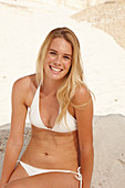 Blonde Frau in weißem Bikini am Strand