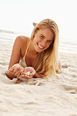 A blonde woman lying on a beach with shells