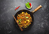 Stir fry soba noodles with chicken, vegetables in old rustic wok pan