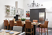 Dining table, leather chairs and black cabinets with integrated fridge in kitchen-dining room