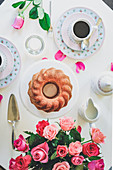 Coconut and cinnamon Bundt cake on a table laid with a bouquet of roses