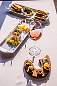 A glass of rose wine with snacks from various cheeses, snails and toasts with pate in the restaurant