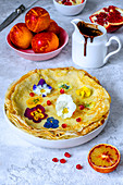 Thin pancakes with violets, chocolate sauce, red oranges and pomegranate