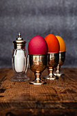 Easter eggs coloured with organic dyes in egg cups with a salt shaker