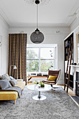 Yellow upholstered sofa, coffee table and classic chair in the living room with gray carpet