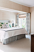 Doppelbett in hellem Schlafzimmer mit Tapete in Beige