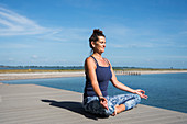 Woman sitting in the lotus position next to the sea