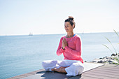 Woman sitting in the lotus position next to the sea