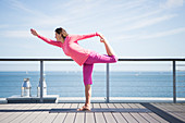 Woman doing yoga on terrace by the sea