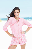 Junge Frau in rosa Bluse und rosa Shorts am Strand