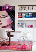 Dining table with shell chairs in front of bookshelf and artwork