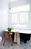 Freestanding bathtub under the louvre window in the small bathroom