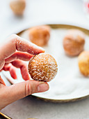 Hand hält Donut Hole mit Zucker