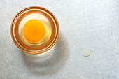 A raw egg in a small glass dish
