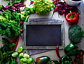 Schiefertafel, umgeben von frischem Gemüse