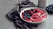 Smoothy of fresh bog blueberries and raspberries in bowl near napkin
